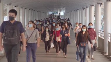 Bangkok, Tayland - 7 Nisan 2020: Kalabalık Asyalılar yaya yolunda yürürken maske takıyor. Coronavirus hastalığı Covid-19 salgını, şehir hayatı veya hava kirliliği konsepti. 4K ağır çekim
