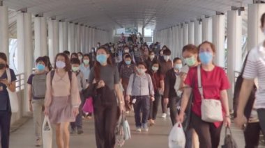 Bangkok, Tayland - 7 Nisan 2020: Kalabalık Asyalılar yaya yolunda yürürken maske takıyor. Coronavirus hastalığı Covid-19 salgını, şehir hayatı veya hava kirliliği konsepti. 4K ağır çekim