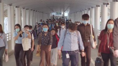Bangkok, Tayland - 7 Nisan 2020: Kalabalık Asyalılar yaya yolunda yürürken maske takıyor. Coronavirus hastalığı Covid-19 salgını, şehir hayatı veya hava kirliliği konsepti. 4K ağır çekim