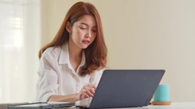 Genç, Asyalı bir kadın ev ofisinde çalışıyor. Bilgisayarı kapat ve işini bitir. Ev hayatı, bilgi teknolojisi, ev hayatı ya da internet uzaktan çalışma konsepti. El kamerası.