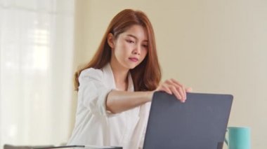 Genç Asyalı kadın ev ofisinde çalışıyor, dizüstü bilgisayarı açıyor ve çalışmaya başlıyor. Ev hayatı, bilgi teknolojisi, ev hayatı ya da internet uzaktan çalışma konsepti. El kamerası.