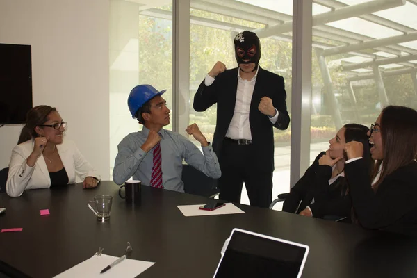 Boss in the office wearing a fighter mask moves to the team enthusiasm the architect and his companions are motivated and laugh accepting challenges and relaxing, the work team raises their fists demonstrating a winning attitude