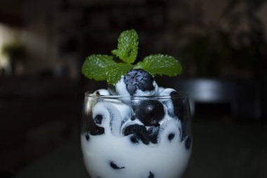 Beyaz yoğurda batırılmış yaban mersini. Meksika 'da taze nane yapraklarıyla süslenmiş cam bardağa.