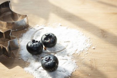 Ay yıldızı figürleri arasındaki yaban mersini şekersiz tatlı taneciklere poz veriyor tatlı olarak ahşap masada ay ve metal yıldızlı