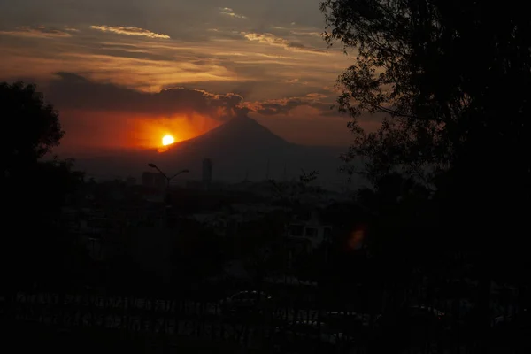 在树林中 普埃布拉市在暮色中得到了庇护 而墨西哥普埃布拉火山的背后隐藏着太阳 — 图库照片