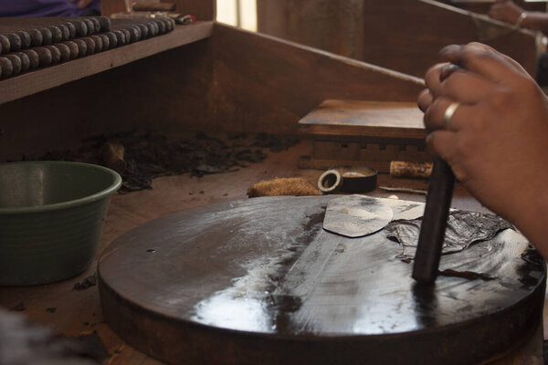 handmade tobacco industry in Mexico city  hands rolling a cigar, scene with tools for the confection of cigars