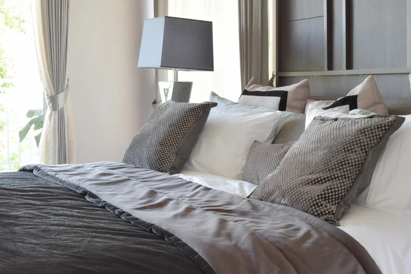 Quarto elegante design de interiores com travesseiros pretos estampados na cama e lâmpada de mesa decorativa . — Fotografia de Stock
