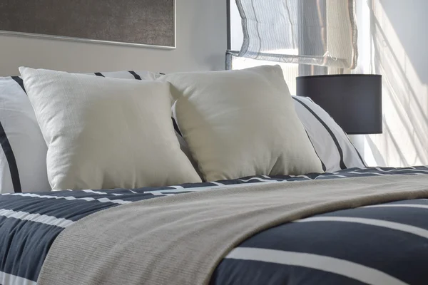 Offwhite and striped pillows on bed with deep blue striped blanket in modern style bedroom — Stock Photo, Image