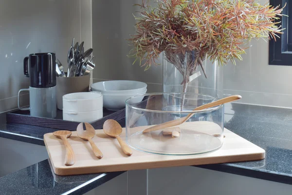 Tigela de vidro com utensílio de madeira na bandeja de madeira na cozinha — Fotografia de Stock
