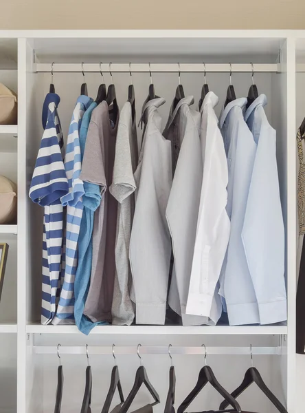 Modern closet with row of shirts hanging in white wardrobe — Stock Photo, Image