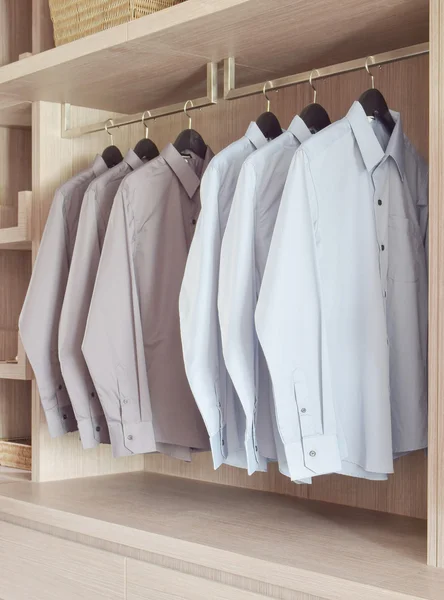 Classic color shirts hanging in warm wooden wardrobe — Stock Photo, Image
