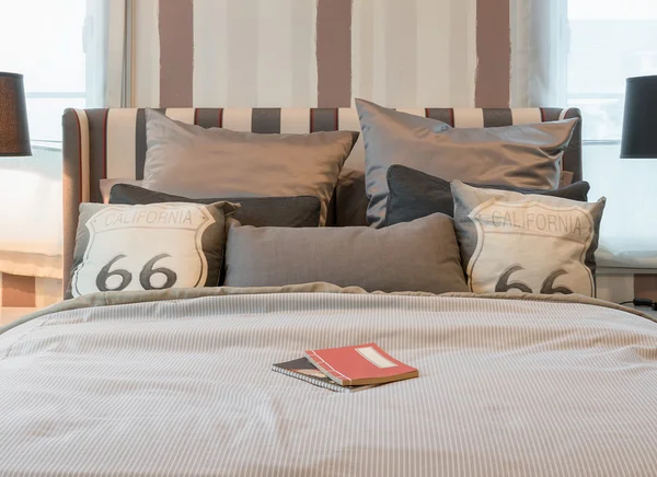 어두운 갈색 베개와 침대 옆 테이블에 독서 용 램프와 아늑한 침실 인테리어 — 스톡 사진