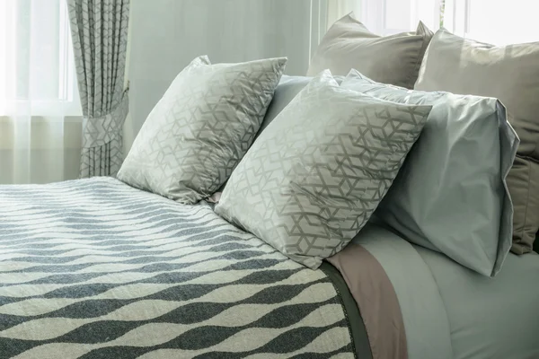 Projektowanie wnętrz stylowe sypialnia z wzorzyste poduszki na łóżku i lampa stołowa dekoracyjne. — Zdjęcie stockowe