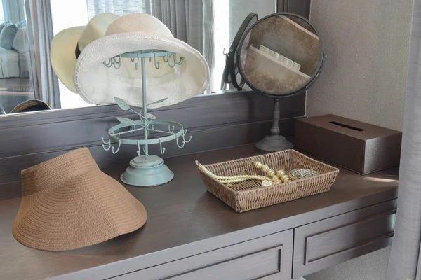 Sombrero blanco y joyas en una mesa de tocador en una habitación contemporánea — Foto de Stock