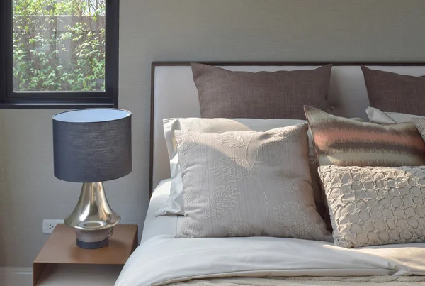 Ajuste de almohadas de estilo elegante en ropa de cama de estilo clásico y lámpara de lectura en la mesita de noche — Foto de Stock