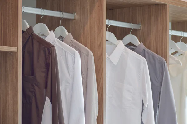 Camisas de color clásico colgando en armario de madera —  Fotos de Stock