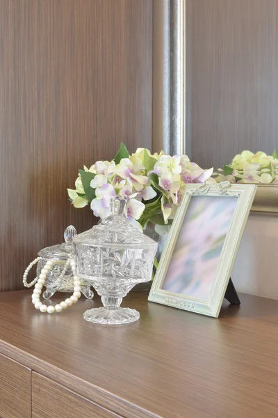 Joyería tarro de cristal con marco de imagen y flores en la mesa de madera — Foto de Stock
