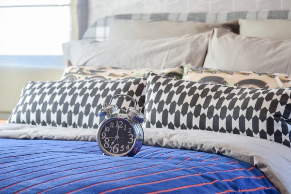 Reloj despertador decorativo con almohadas en blanco y negro en la cama en el dormitorio moderno — Foto de Stock