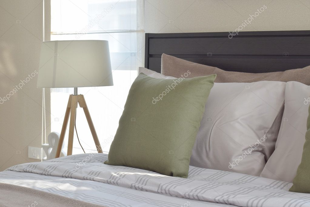 modern bedroom interior with green pillow and decorative wooden lamp on bedside table