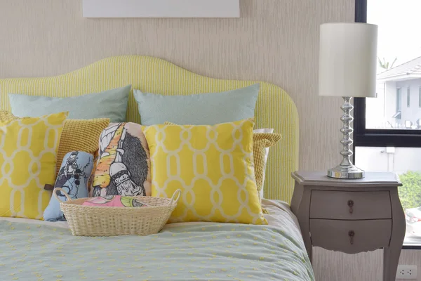 Желтые и зеленые подушки и шаблон на кровати классического стиля и лампы чтения на тумбочке — стоковое фото