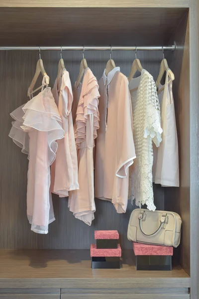 Сладкие пастельные блузки висят в открытом деревянном шкафу — стоковое фото