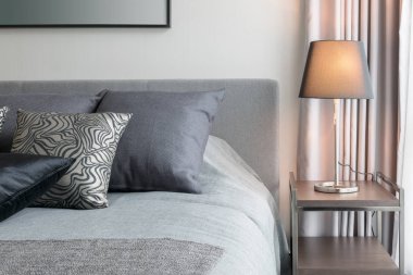 siyah desenli yastık yatak ve dekoratif masa lambası ile şık yatak odası iç tasarım.