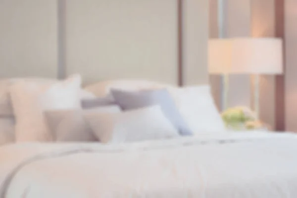 Размытое изображение классического интерьера спальни с подушками и лампой для чтения на тумбочке — стоковое фото