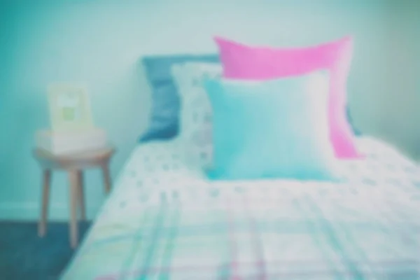 Bild von hellblauen und rosa Kissen auf süßem Bettzeug und Bilderrahmen auf dem Nachttisch verschwimmen — Stockfoto
