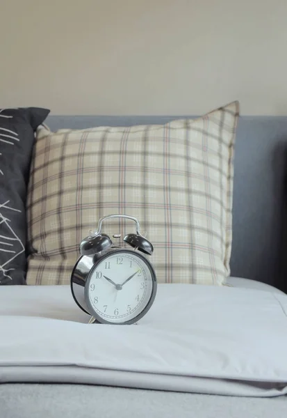 Despertador y almohadas de patrón gráfico en la cama — Foto de Stock