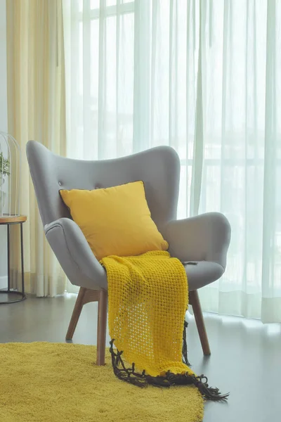 Yellow scarf and yellow pillow setting on gray color easy armchair in living room — Stock Photo, Image