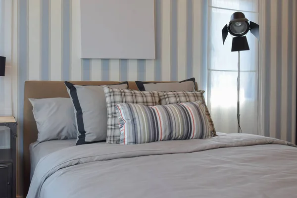 Стильный дизайн интерьера спальни с полосатыми подушками на кровати и декоративной настольной лампой . — стоковое фото