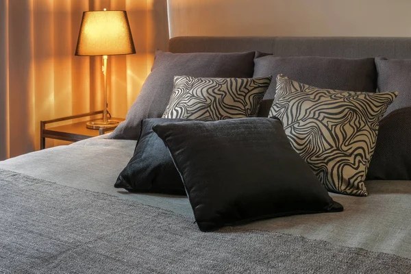 Стильний дизайн інтер'єру спальні з чорними подушками на ліжку та декоративною настільною лампою . — стокове фото