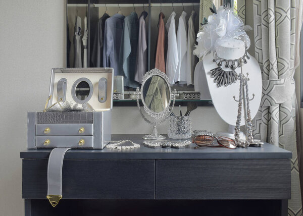 table mirror,sunglasses,jewelry and makeup brushes on a black dressing table