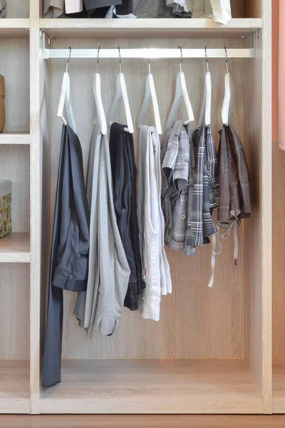 Placard moderne avec rangée de pantalons suspendus dans une armoire en bois — Photo