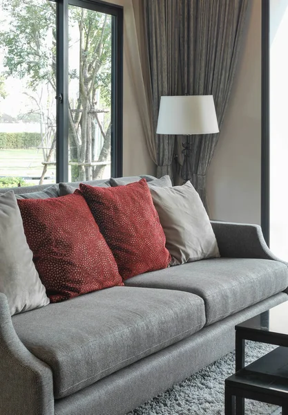 Moderni olohuone suunnittelu punaiset tyynyt sohvalla ja koristeellinen pöytävalaisin — kuvapankkivalokuva