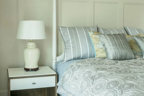Уютный интерьер спальни с подушками и лампой для чтения на тумбочке — стоковое фото