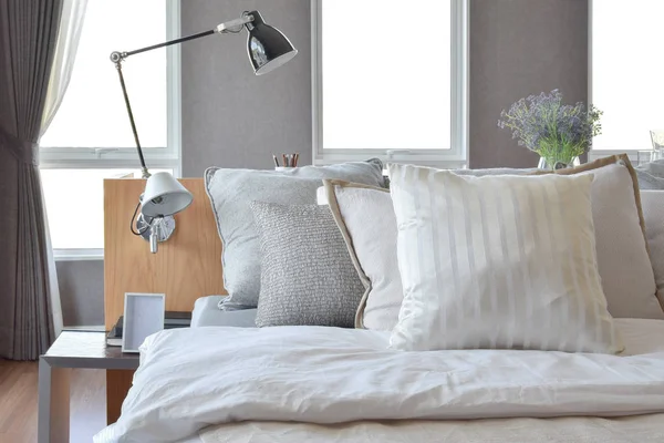 Stijlvolle slaapkamer interieur met wit gestreepte kussens op bed en decoratieve tafellamp. — Stockfoto