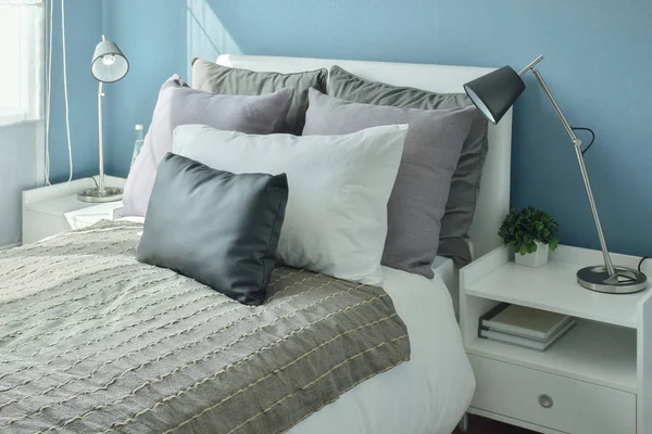 Almohadas grises, grises oscuros y beige en la cama con dormitorio de pared azul —  Fotos de Stock