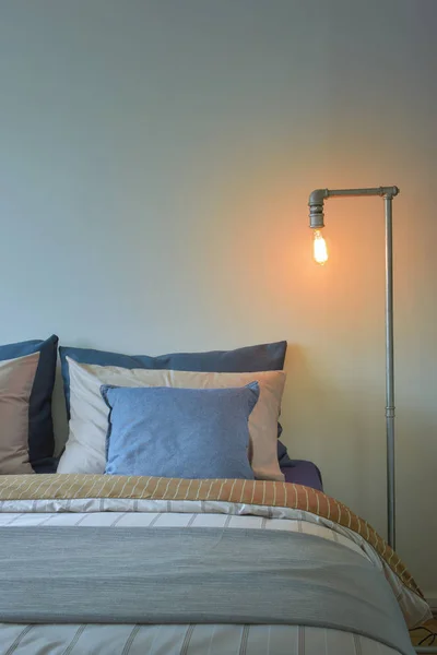 Промисловий стиль читання лампи і сині подушки на сучасній постільній білизні — стокове фото