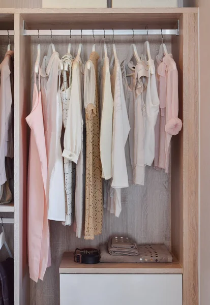Moderner Kleiderschrank mit einer Reihe von Kleidern, die im Holzschrank hängen — Stockfoto