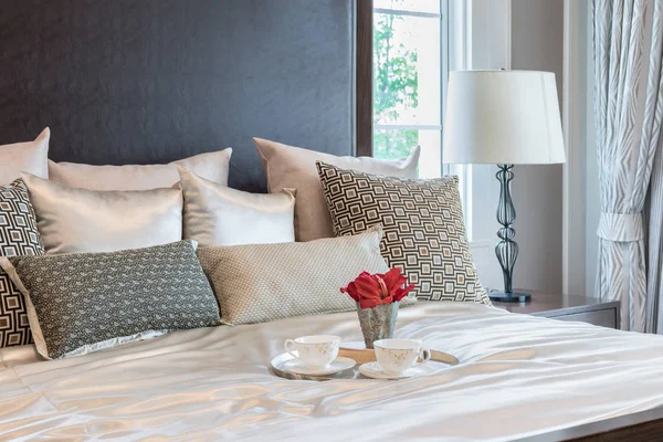 Роскошный интерьер спальни с коричневым шаблоном подушки и декоративный поднос с цветами на кровати — стоковое фото