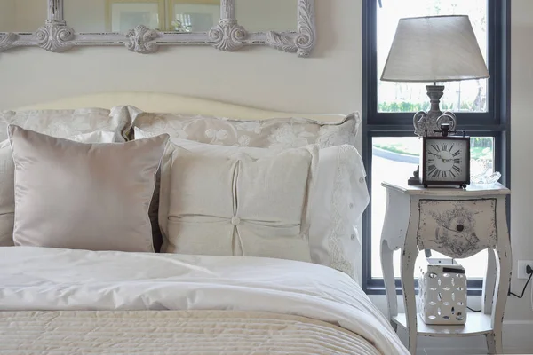 Luxe slaapkamer interieur met klassieke tafellamp en klok op het nachtkastje — Stockfoto