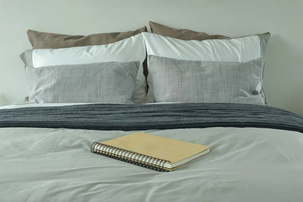 Cuaderno en la cama con el esquema de color gris ropa de cama — Foto de Stock