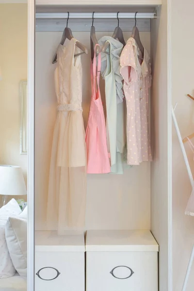 Row of colorful dress hanging on coat hanger in white wardrobe — Stock Photo, Image