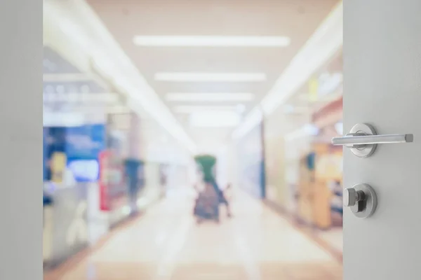 opened white door to blur of department store with bokeh as background.