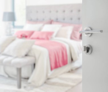 modern bir evde yatakta bulanık renkli yastıklar beyaz kapı açıldı