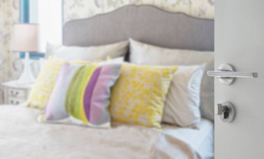 modern bir evde yatakta bulanık renkli yastıklar beyaz kapı açıldı