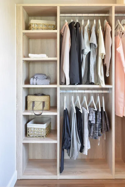Современный шкаф с рядами тканей, висящих в деревянном шкафу — стоковое фото