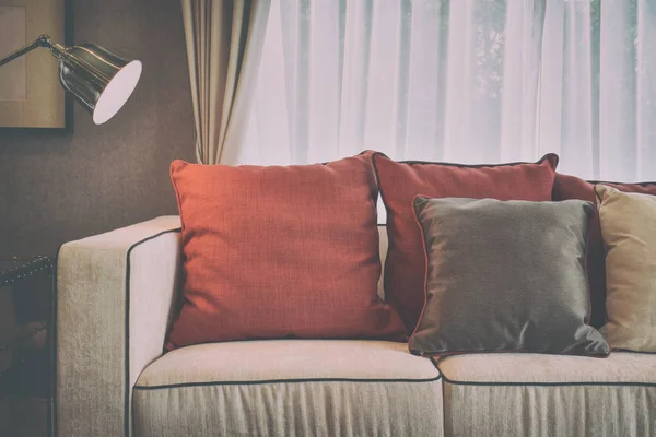 Travesseiros de linho marrom vermelho e profundo no sofá de linho bege com uma lâmpada de latão na moderna sala de estar clássica efeito de cor vintage — Fotografia de Stock