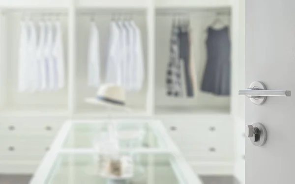 Öppnat vit dörr att gå i garderob rum med vit hatt och smycken set på ett dresser bord — Stockfoto